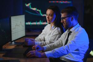 Team of stockbrokers are having a conversation in a dark office with display screens photo