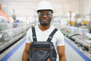 Portrait of industrial engineer. Smiling factory worker with hard hat standing in factory production line photo