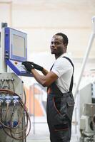Portrait of African American male engineer in uniform and standing in industrial factory photo