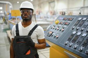 Portrait of African American male engineer in uniform and standing in industrial factory photo