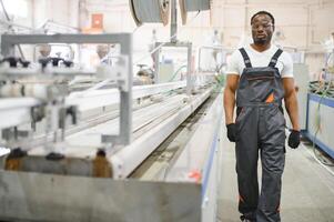 Portrait of African American male engineer in uniform and standing in industrial factory photo