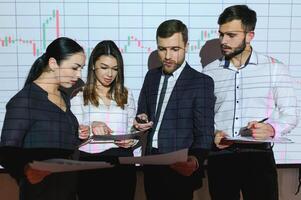 Group of business people working at modern office.Technical price graph, red and blue candlestick chart and stock trading computer screen background. Double exposure. Traders analyzing data photo
