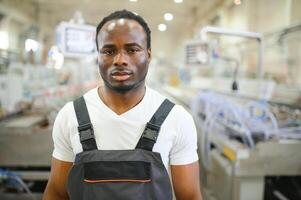 Portrait of African American male engineer in uniform and standing in industrial factory photo