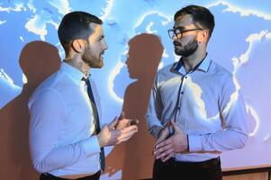 Two Business Colleagues Have Informal Meeting On Stairs Of Office With World Map In Background photo