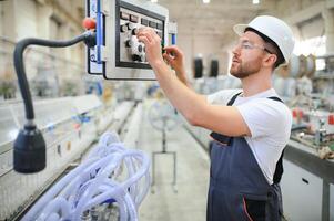 Smiling and happy employee. Industrial worker indoors in factory. Young technician with hard hat photo