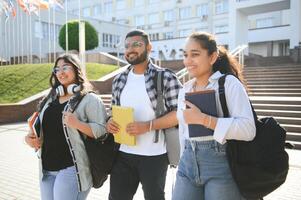 Portrait of three multi-ethnic university students embracing together standing in the campus photo