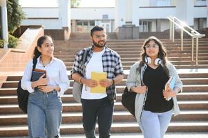 Portrait of three multi-ethnic university students embracing together standing in the campus photo