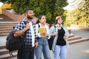 Portrait of three multi-ethnic university students embracing together standing in the campus photo