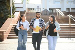 Portrait of three multi-ethnic university students embracing together standing in the campus photo