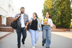 Portrait of three multi-ethnic university students embracing together standing in the campus photo
