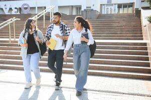 Portrait of three multi-ethnic university students embracing together standing in the campus photo