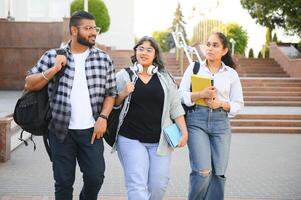 Portrait of three multi-ethnic university students embracing together standing in the campus photo