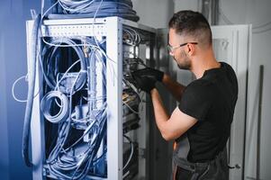Repairman is busy and working with internet equipment and wires in server room photo