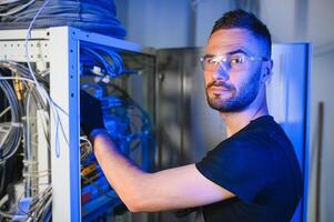 Repairman is busy and working with internet equipment and wires in server room photo