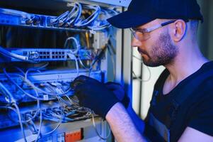 Repairman is busy and working with internet equipment and wires in server room photo