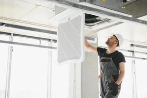 Worker repairing ceiling air conditioning unit photo