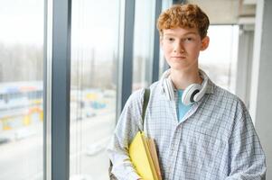 A young guy college student with a backpack is standing in the hall of the university photo