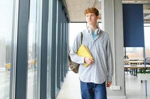 A young guy college student with a backpack is standing in the hall of the university photo
