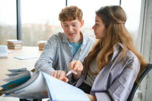 students sit at shared desk making notes studying together at university photo
