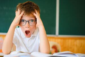 Portrait of a confused or surprised student at a desk in a classroom photo