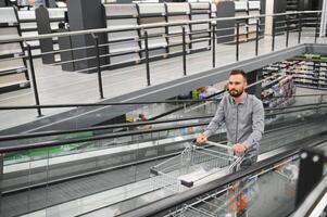 A man with a shopping cart on an escalator in a hardware store. photo
