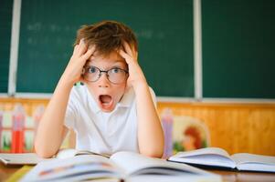 Portrait of a confused or surprised student at a desk in a classroom photo