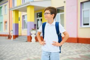 Back to school. Pupil of primary school on the way to study. Little first grader in glasses and with school bag photo