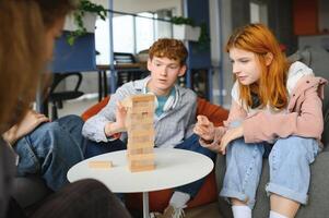 group of young friends playing board games together while sitting around table photo