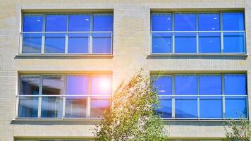 New modern block of flats in green area. Eco apartment building saving energy and fresh air concept. Green tree and new apartment building. The harmony of nature and modernity. photo