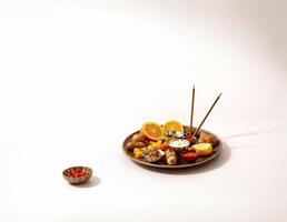 a traditional thali plate with offerings of food and incense stick on white background photo