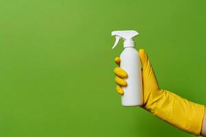 hand in yellow rubber glove holding plastic spray bottle, cleaning detergent on a isolated background. photo