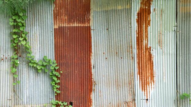 An image of corrugated zinc with rust patches, displaying the textured surface and weathered appearance. photo