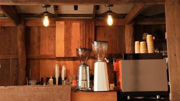 A well-equipped coffee machine along with brewing tools displayed in a coffee shop with warm brown wooden panels. photo