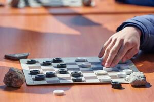 Outdoor checkers tournament on paper checkerboard on table, close up players hands photo