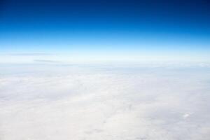 Over clouds aerial top view from aircraft window, thick white blue clouds looks like soft foam photo