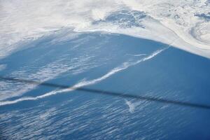 Aerial view from airplane window over clouds to frozen sea with north steam gas pipeline underwater photo