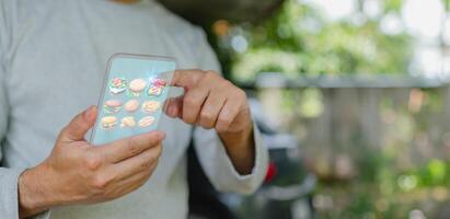 A man is holding a cell phone and pointing at a menu of food items. The menu includes a variety of items such as sandwiches, pizza, and other snacks photo