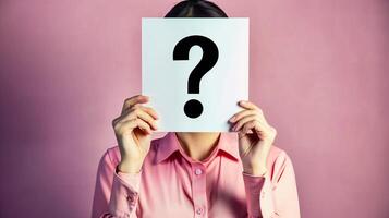 A woman holding up an empty white card with the question mark symbol on it in front of her face photo