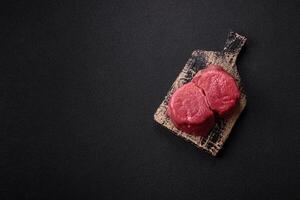 Fresh juicy raw beef medallions with salt and spices photo