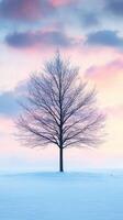 A solitary tree stands in snow under a pastel sky at dusk photo