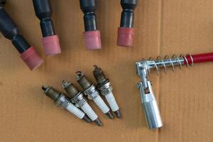 Top view composition of used spark plugs. With spark plug wrench and spark plug socket. Place on brown paper. photo