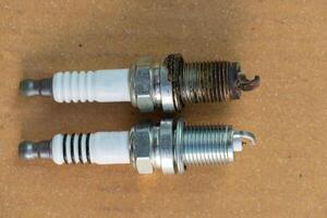 Compare new and old spark plugs. On the stained brown paper. photo