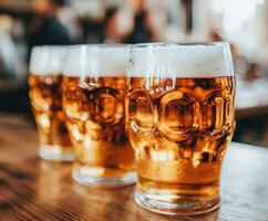 Beer mugs filled with foam on a wooden bar table in a lively pub photo