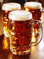 Freshly poured beer mugs on a wooden bar table in the evening photo