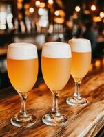 Three beer mugs with foam on a wooden table in a lively bar photo