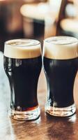 Two glasses of dark and light beer on a wooden bar counter photo