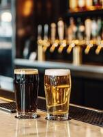 Two glasses of dark and light beer on a bar counter at a pub photo