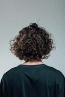 Young man with curly hair facing away in a minimalist studio photo