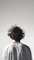 Young man with curly hair facing a plain background in a casual shirt photo