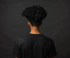 Young man with curly hair faces away against a dark backdrop photo